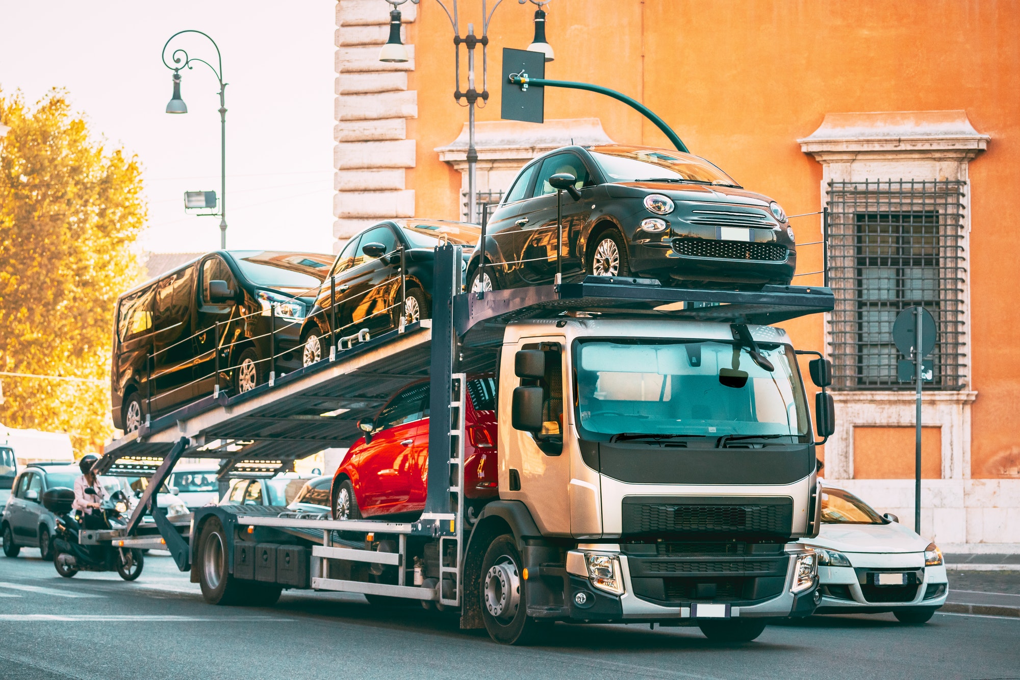 Auto-transport Carrying New Fiat Cars In European City Street. Auto Transport Broker Or Car