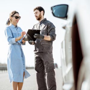 Worker with woman near the broken car on the highway