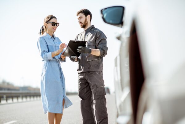 Worker with woman near the broken car on the highway